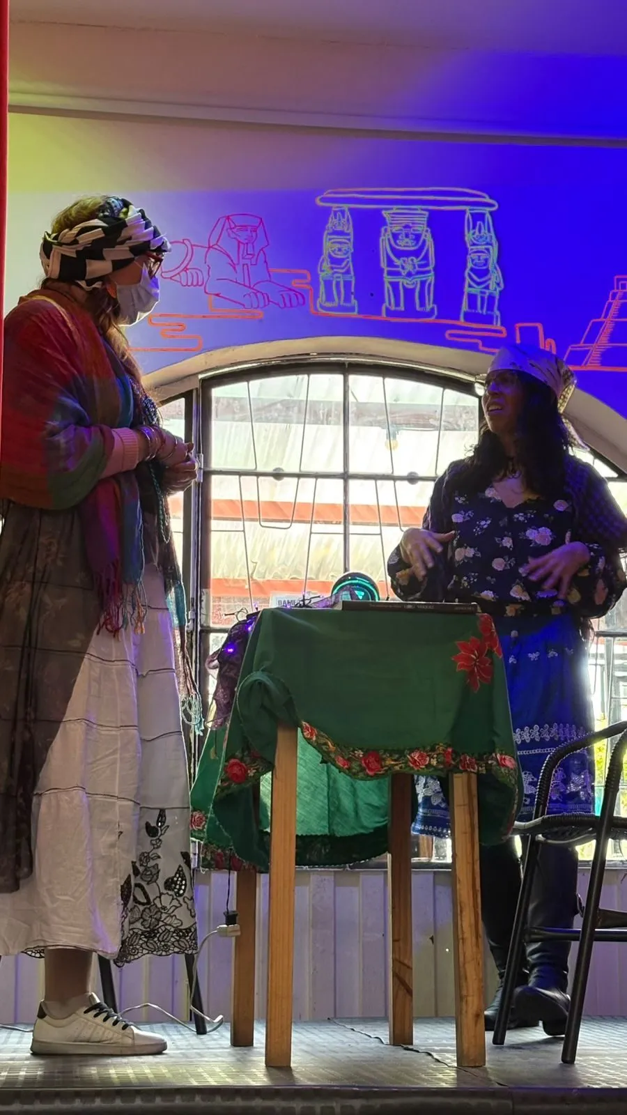 Una alumna con un chal de colores da la réplica a otra, de pie sobre el escenario