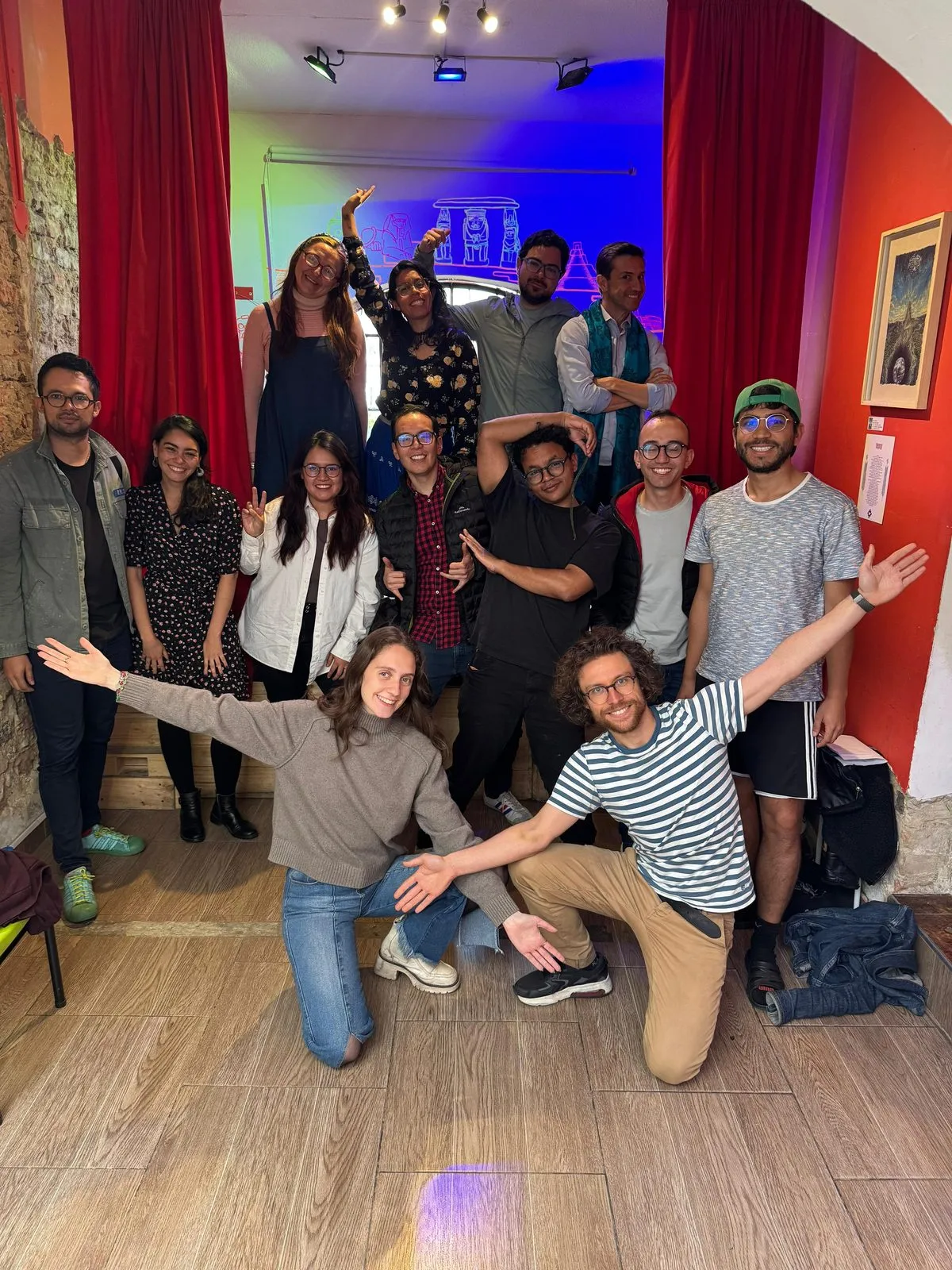 El grupo del taller posa entero al terminar, delante de las cortinas rojas del escenario